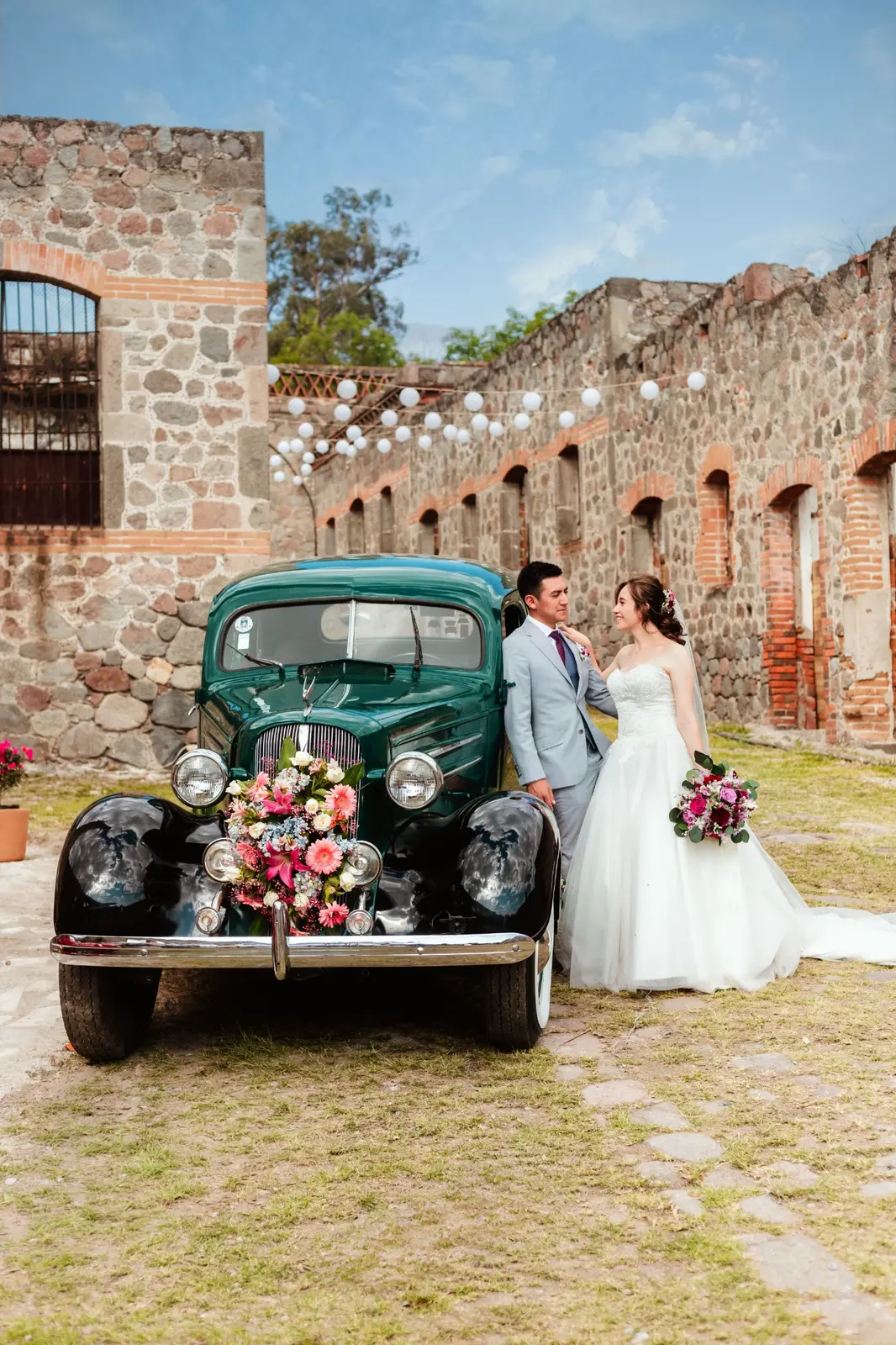 Los novios junto a un automóvil clásico decorado con flores